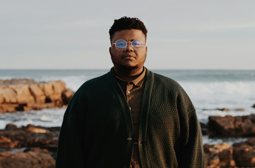 Portrait of a man with short dark hair and glasses in a sweater