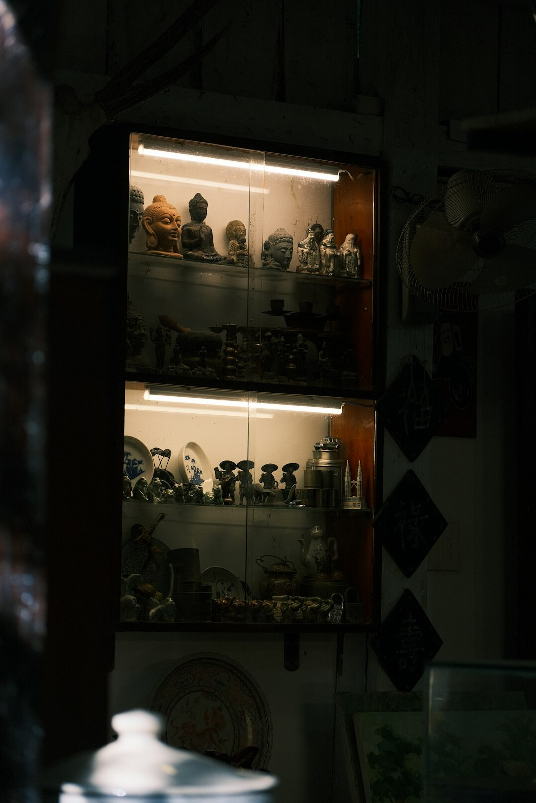 Private collection display cabinet with antique objects in warm light